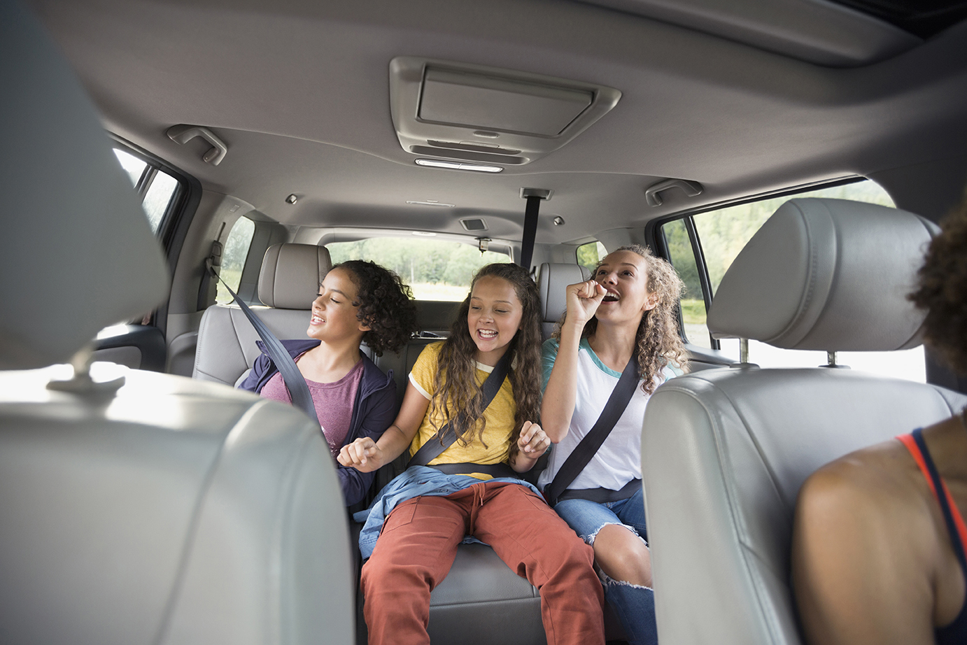 A group of young girls in the backseat of a used car. 
